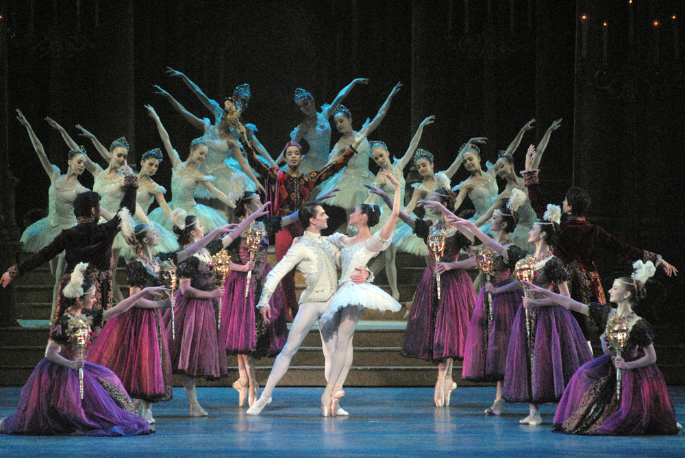 Soloist performing a technically demanding classical variation on a dimly lit stage with dramatic spotlighting