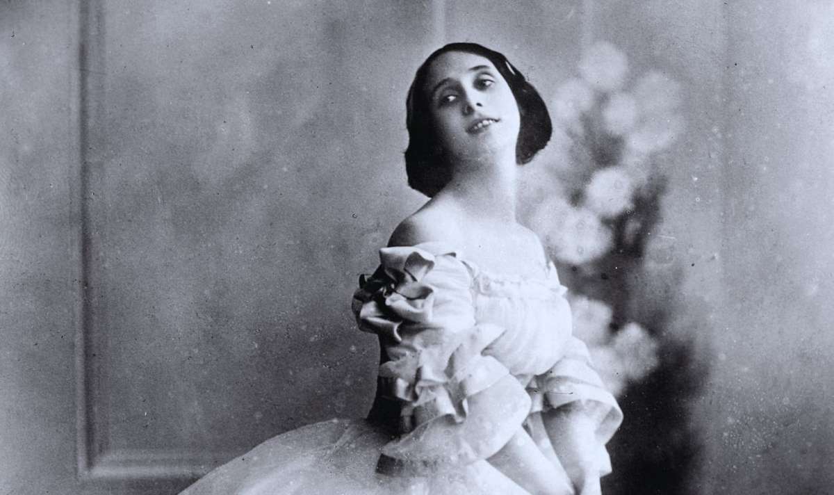 Young Anna Pavlova in a practice class at the St. Petersburg Imperial Ballet School wearing a simple rehearsal dress