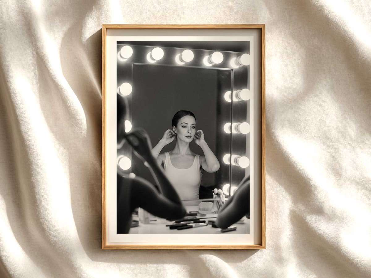Ballerina adjusting her posture at the barre with a clear mirror reflection showing focused expression