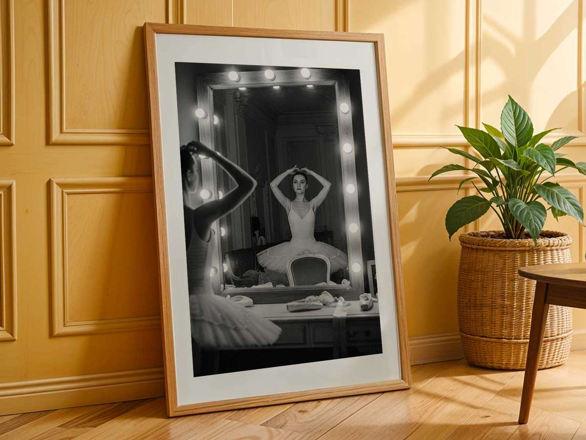 Wide-angle view of a rehearsal where a dancer composes a complex gesture, the mirror doubling the composition and enriching…