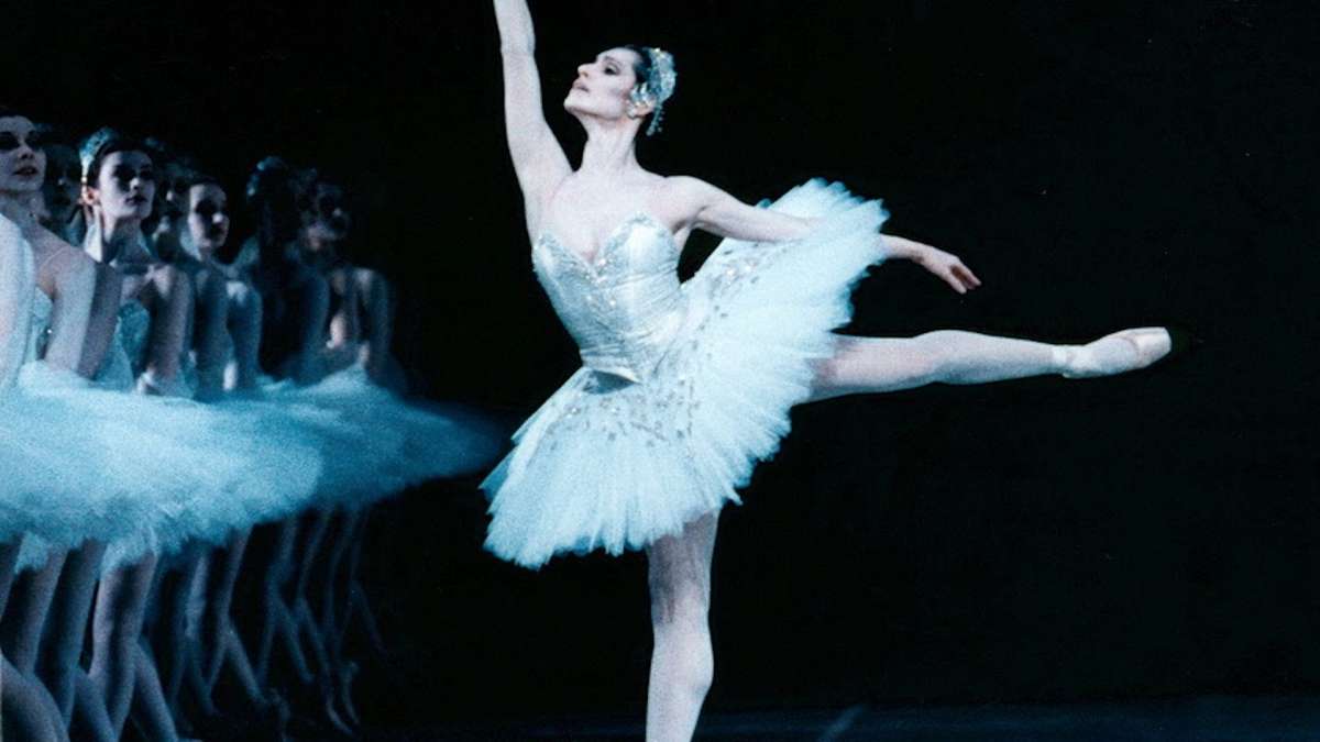 Marie‑Claude Pietragalla poised center stage, spotlight highlighting her strong posture and intense expression