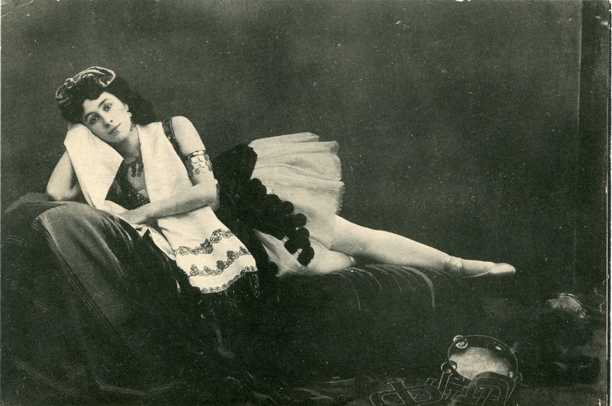 Mathilde Kschessinska in a classical tutu performing an intricate arm and foot pose on stage