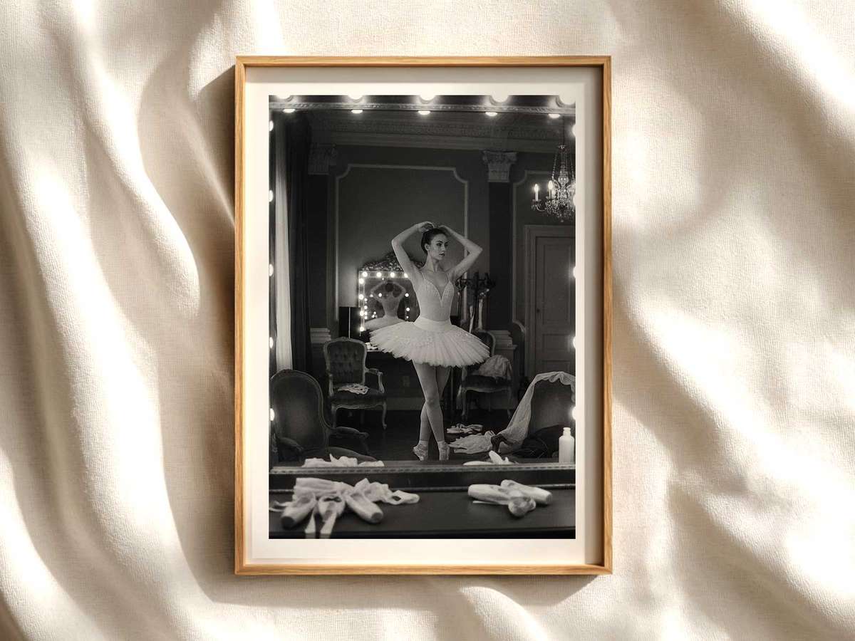 Ballerina in a deep plié facing a tall mirror, her reflection aligning with her body to create doubled lines