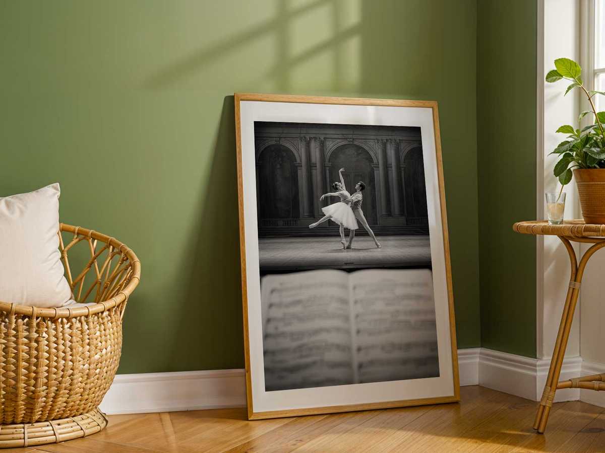 Single spotlight illuminating a ballerina poised on one foot, the surrounding stage left in soft shadow