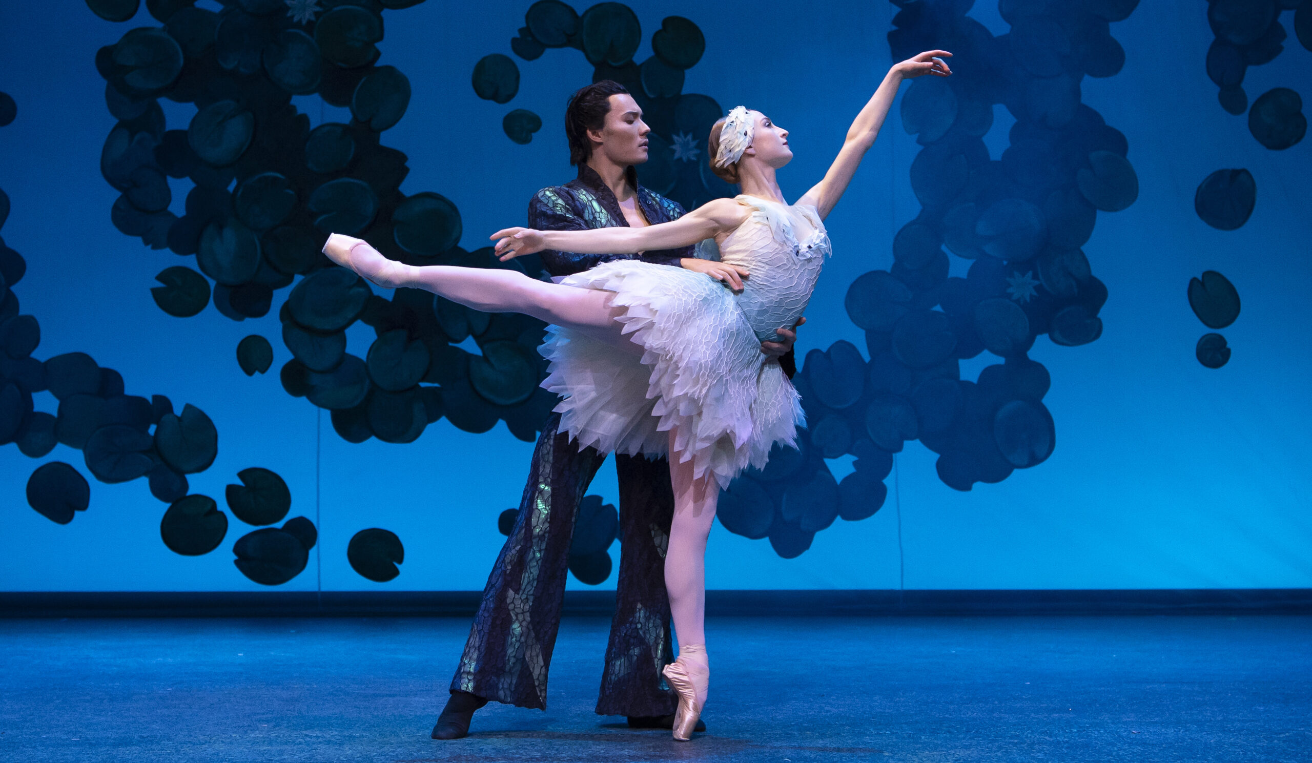Two dancers in white tutus performing a lyrical pas de deux on a moonlit stage, reflecting Swan Lake’s ethereal purity